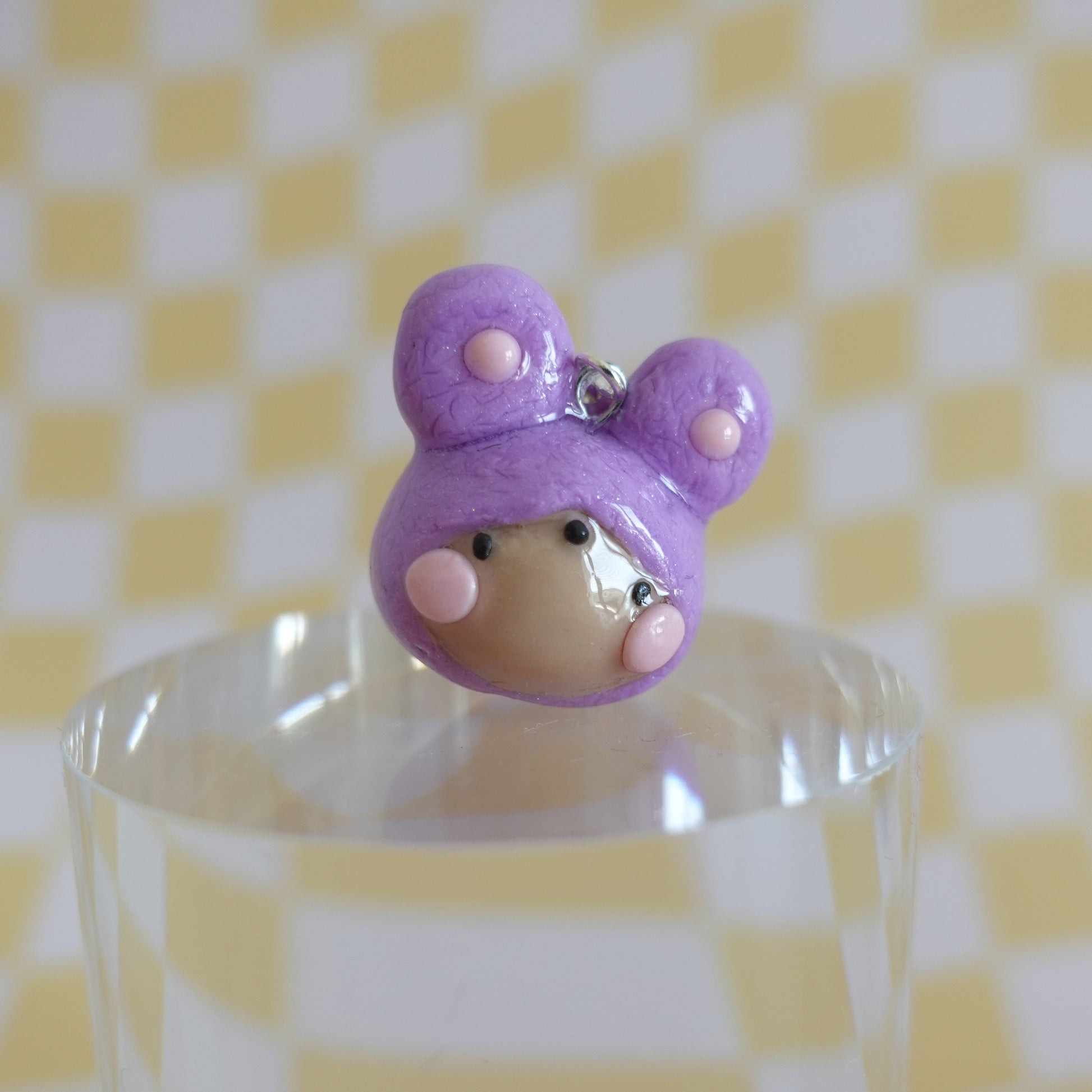 Close-up of a handmade polymer clay earring in purple on a silver-plated copper hook.