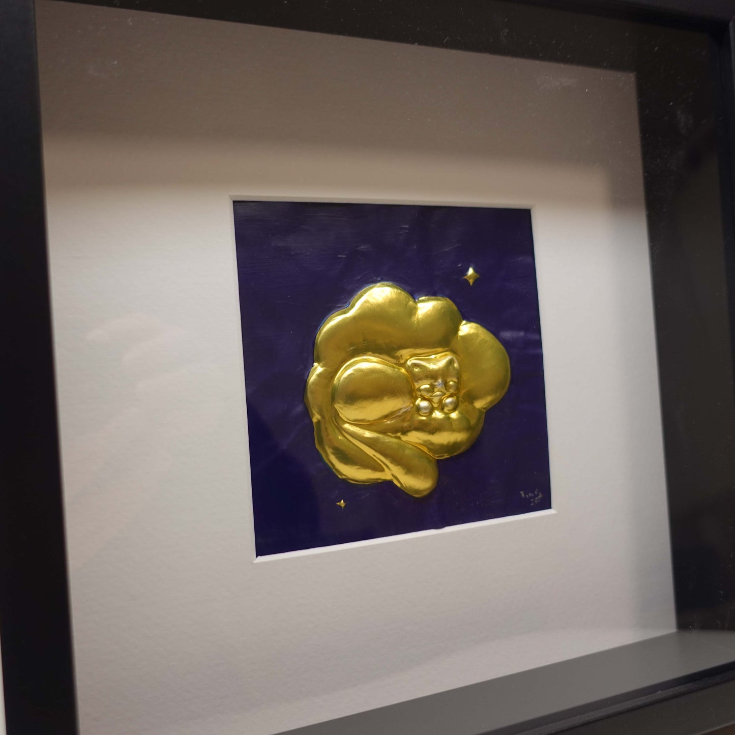 Dreamlike wall artwork featuring a sculpted brass cat sleeping in the clouds, framed with depth and a soft blue painted backdrop.