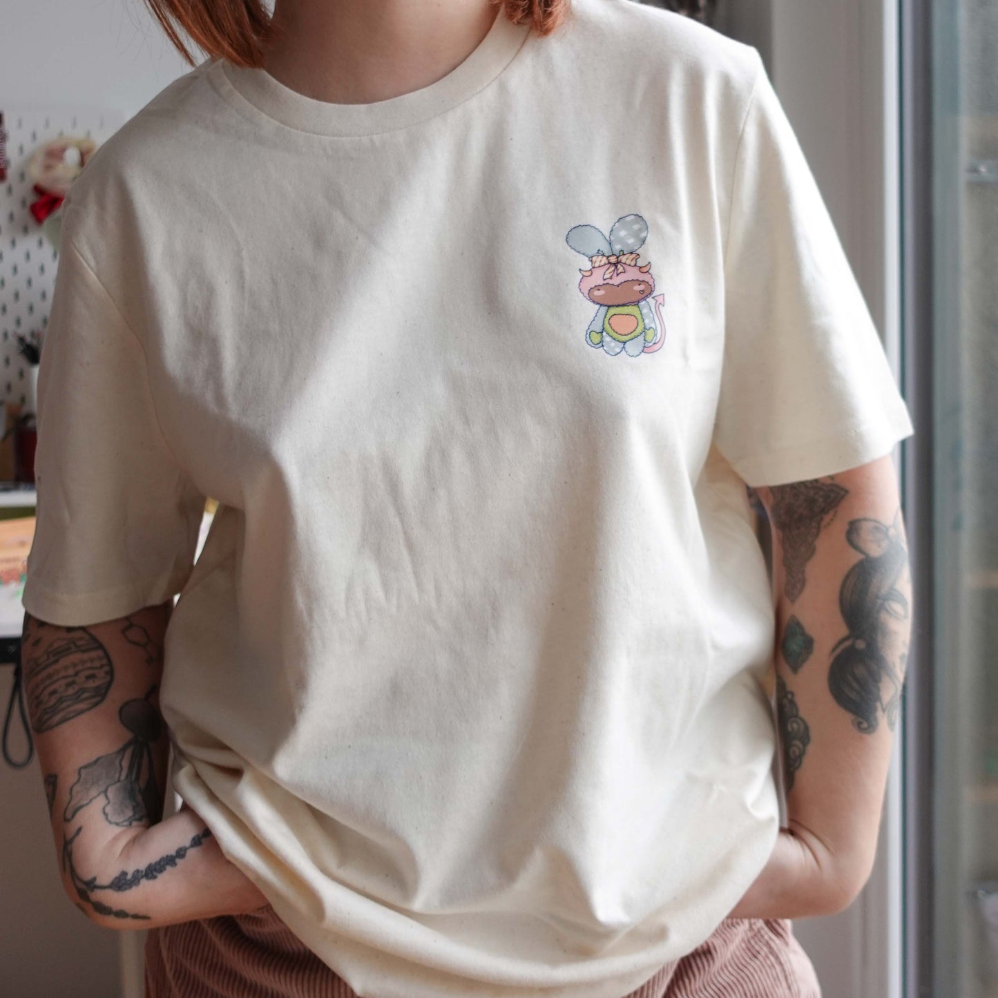 Front view of the Fluff Club t-shirt in natural raw color, featuring a original design by uncomfy cherry from the devil hearts sticker pack