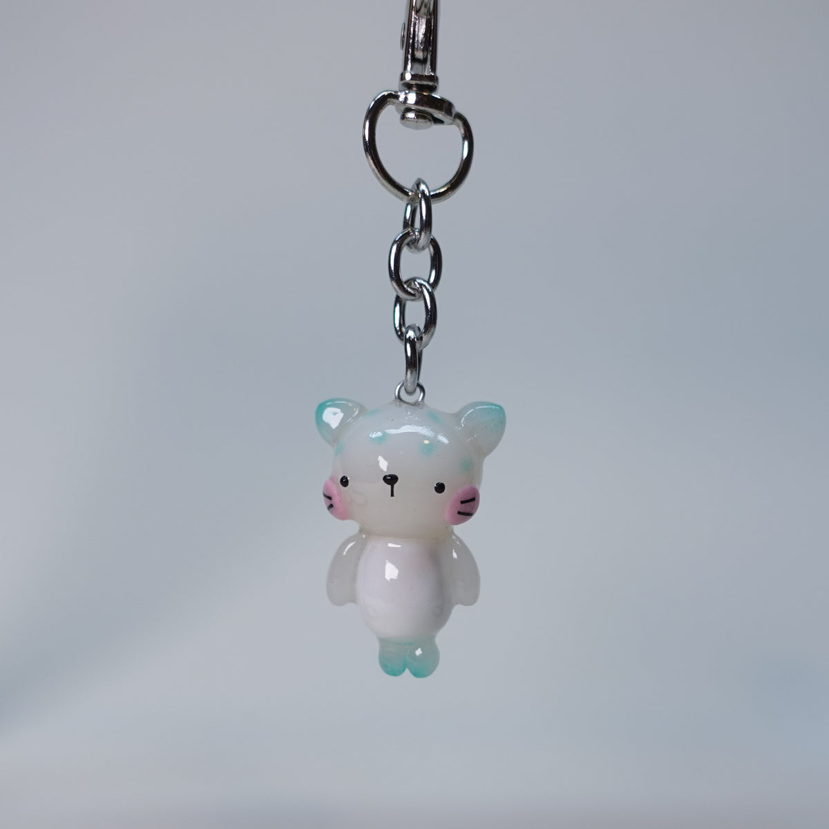 Handcrafted teal pastel cat keychain with smooth finish and playful small cat design, limited edition handmade accessory for keys or bags.
