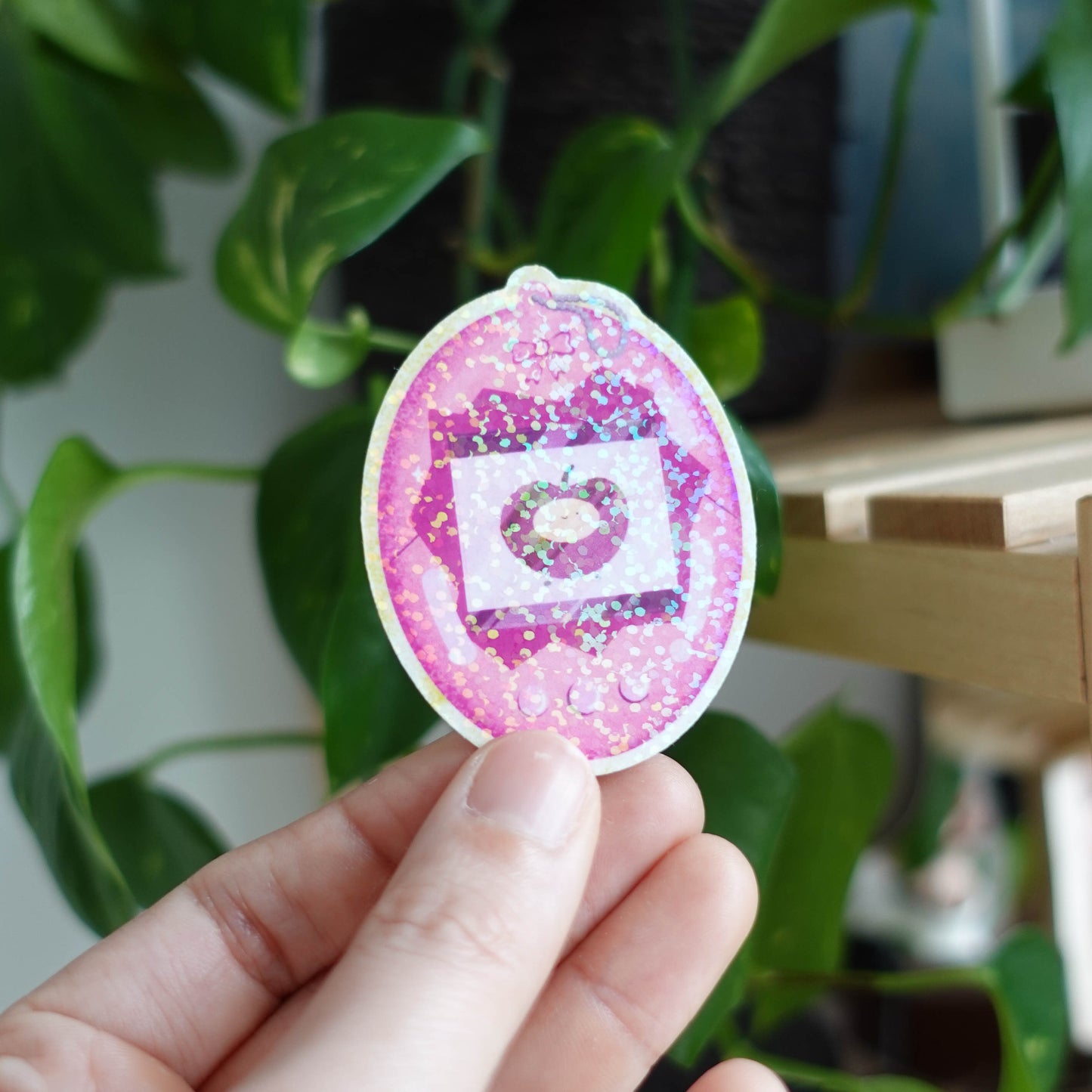 Tamagotchi Cherry sticker featuring an adorable virtual pet surrounded by cherry blossoms, perfect for adding retro charm to laptops, notebooks, and water bottles.