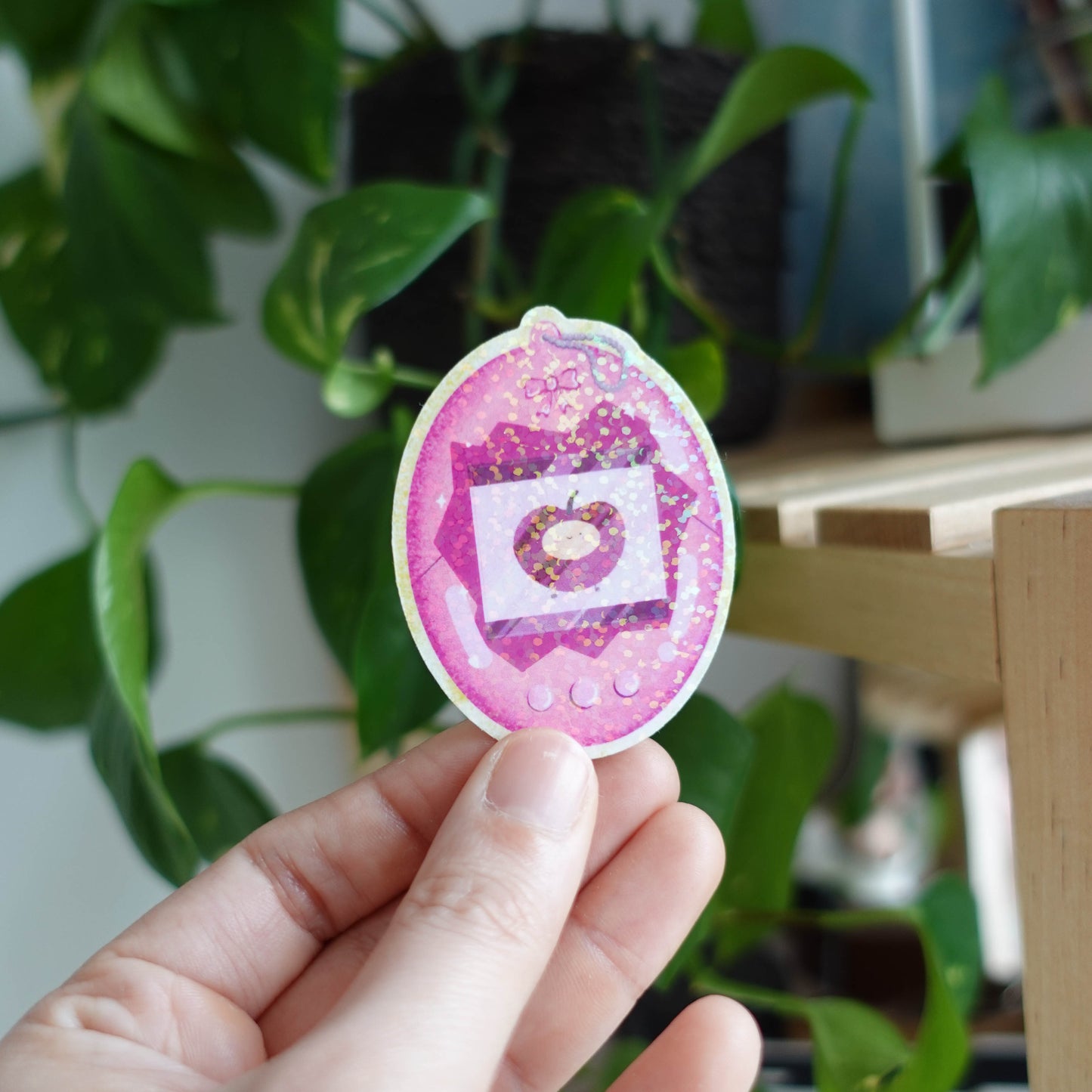 Tamagotchi Cherry sticker featuring an adorable virtual pet surrounded by cherry blossoms, perfect for adding retro charm to laptops, notebooks, and water bottles.