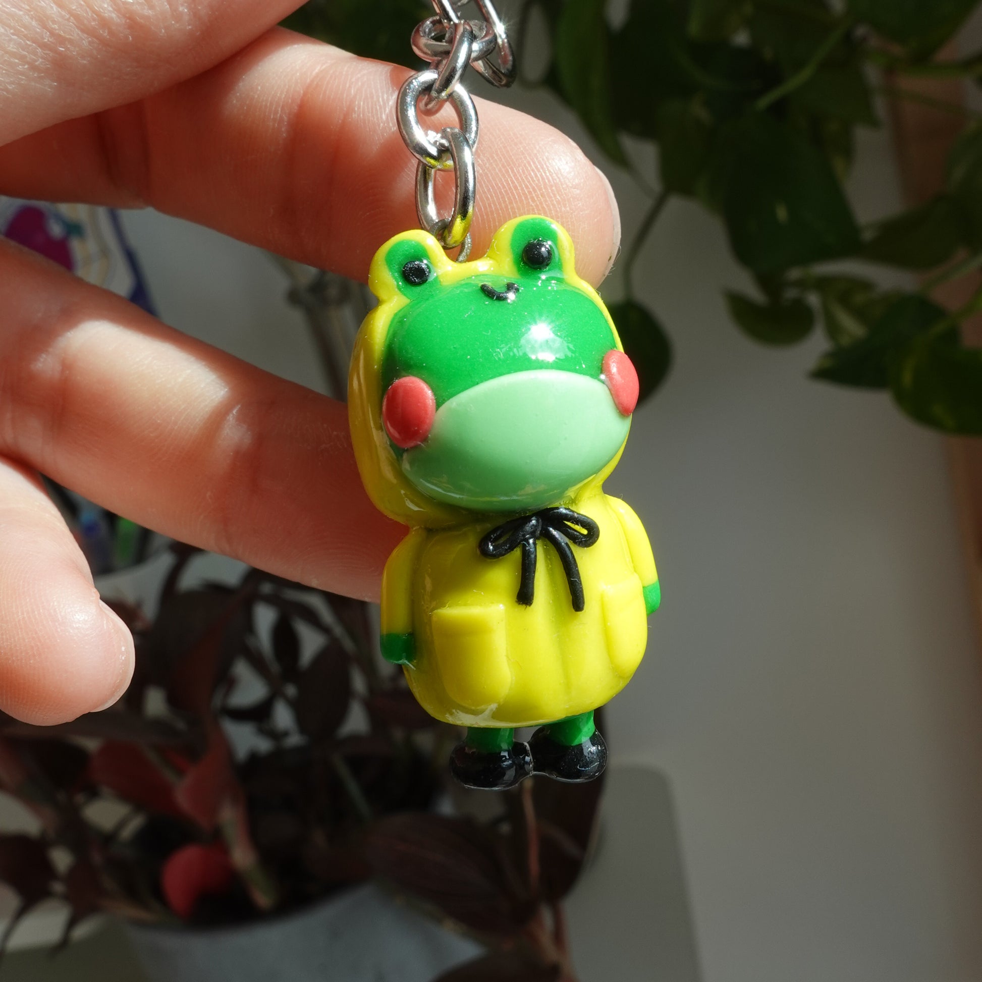 A cute frog keychain wearing a yellow raincoat and boots, adding charm to your accessories.