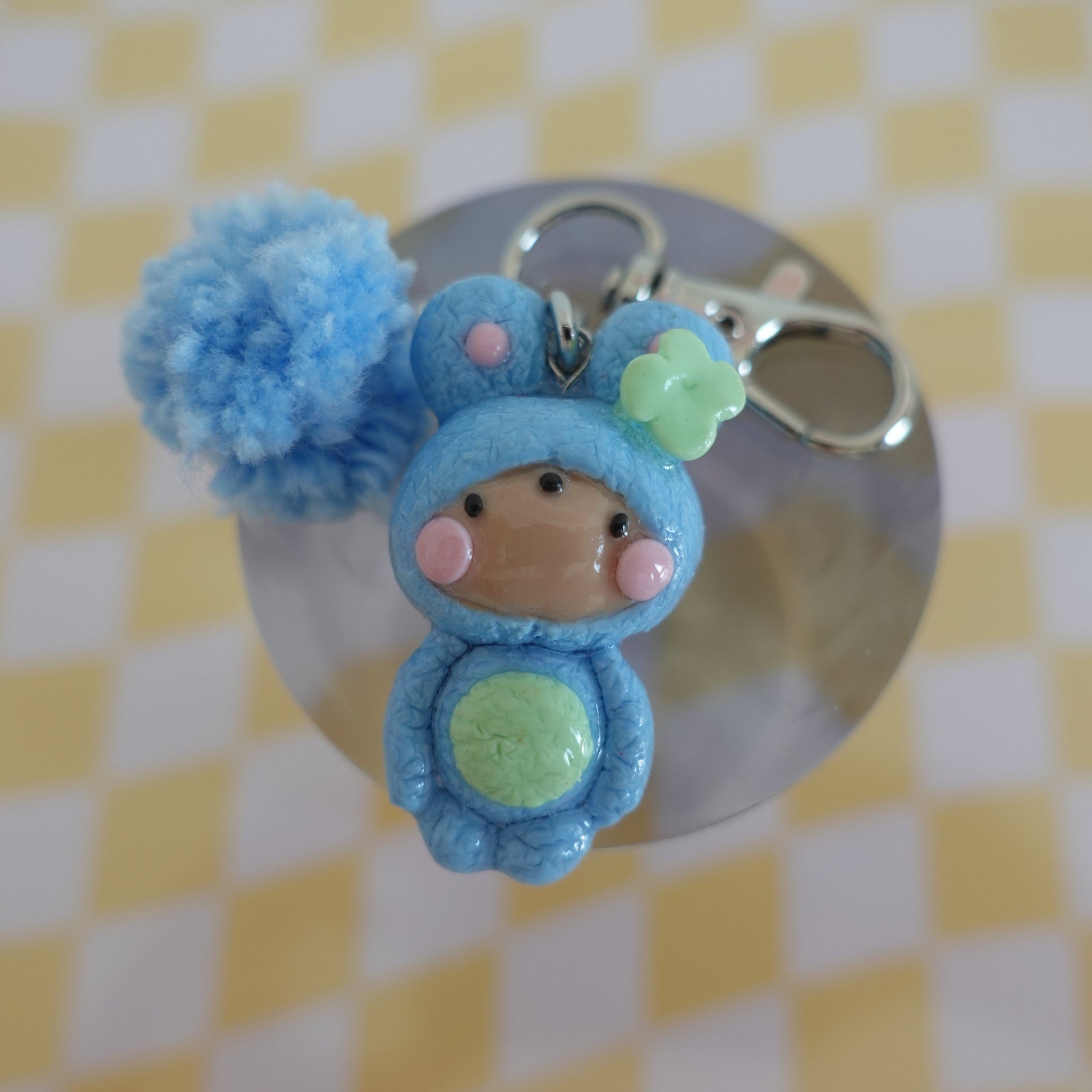 Close-up of a handmade polymer clay keychain in blue with an extra charm fluff, showcasing its unique design.