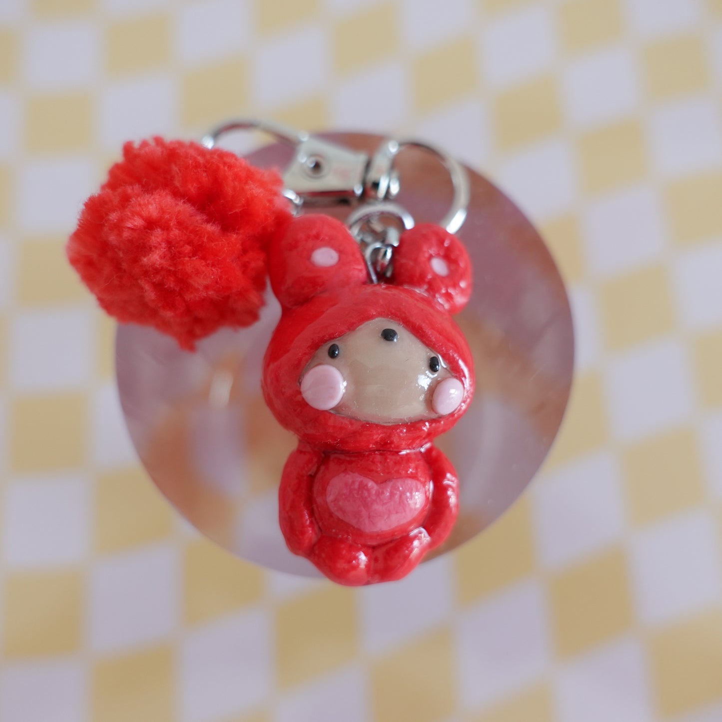 Close-up of a handmade polymer clay keychain in red featuring an extra charm fluff and distinctive handcrafted details.