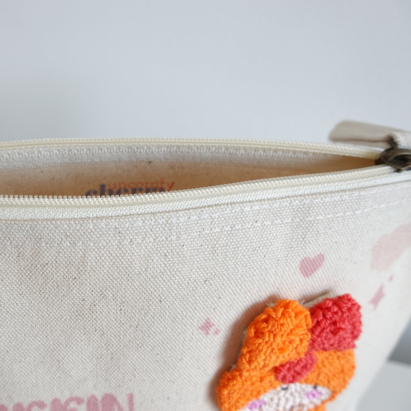 Side view of the Fluff Club craft pouch, showing the fair trade cotton material and punch needle detail.