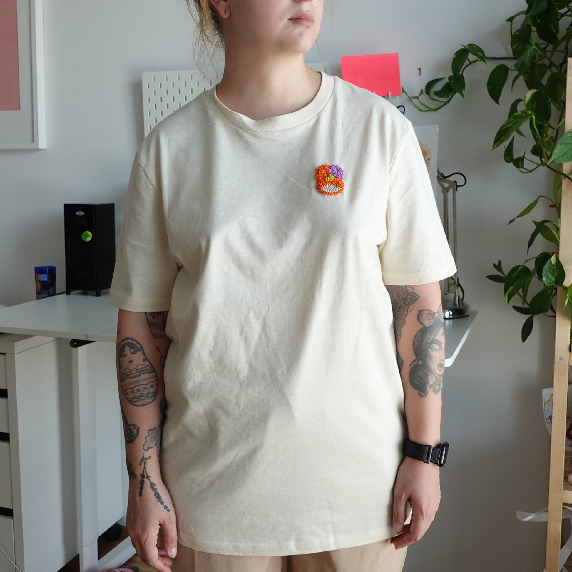 Front view of the Fluff Club punch needle t-shirt in natural raw color, featuring a handmade punch needle detail on the chest.