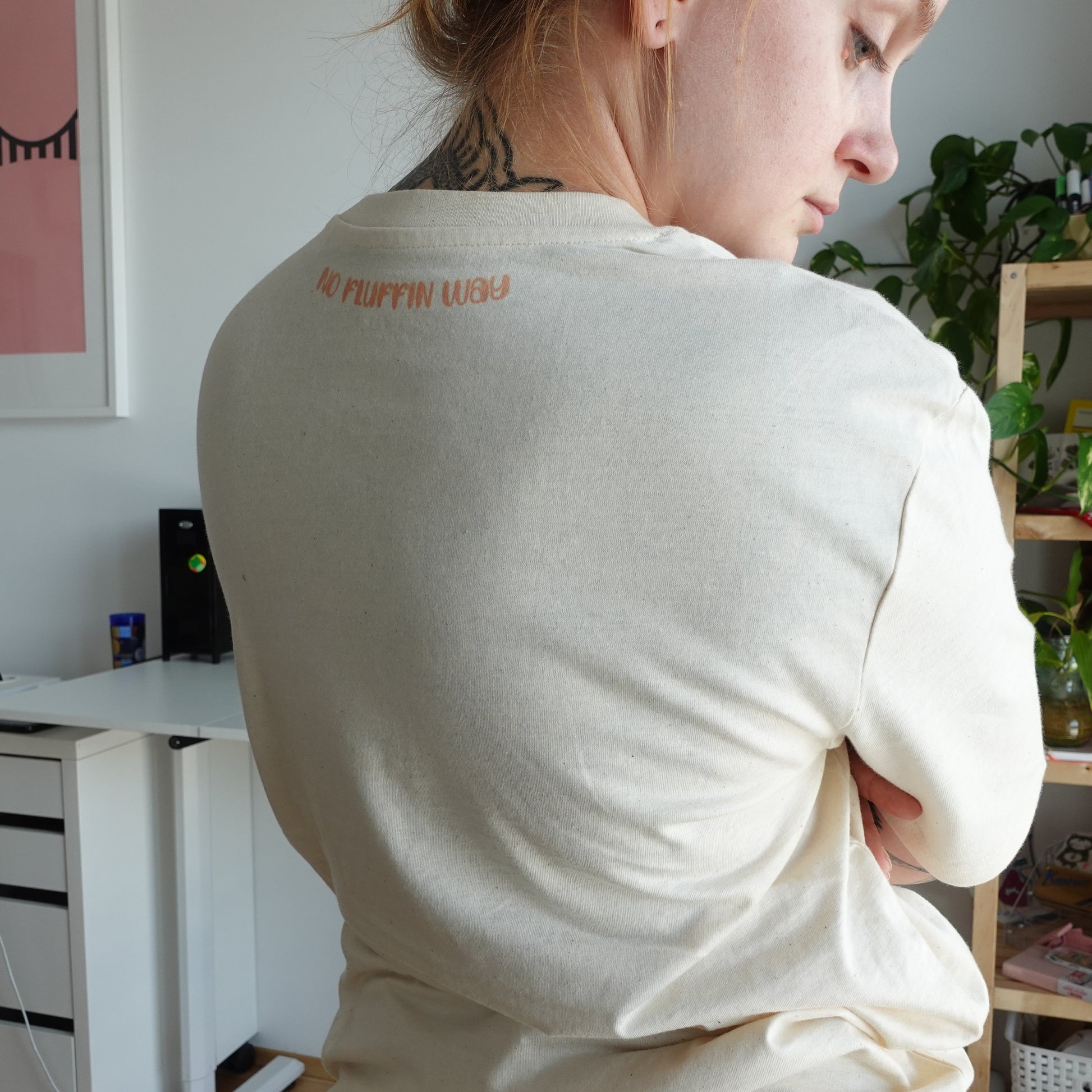 Back view of the Fluff Club punch needle t-shirt in natural raw color, showing the unique print at the neckline.