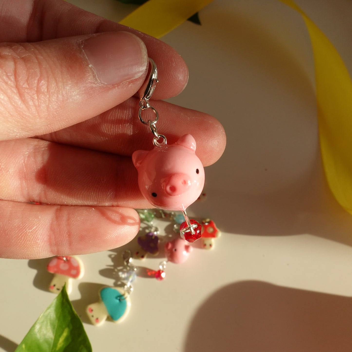 little pig lucky charm with a red bead out of polymer clay and covered with uv resin for durability