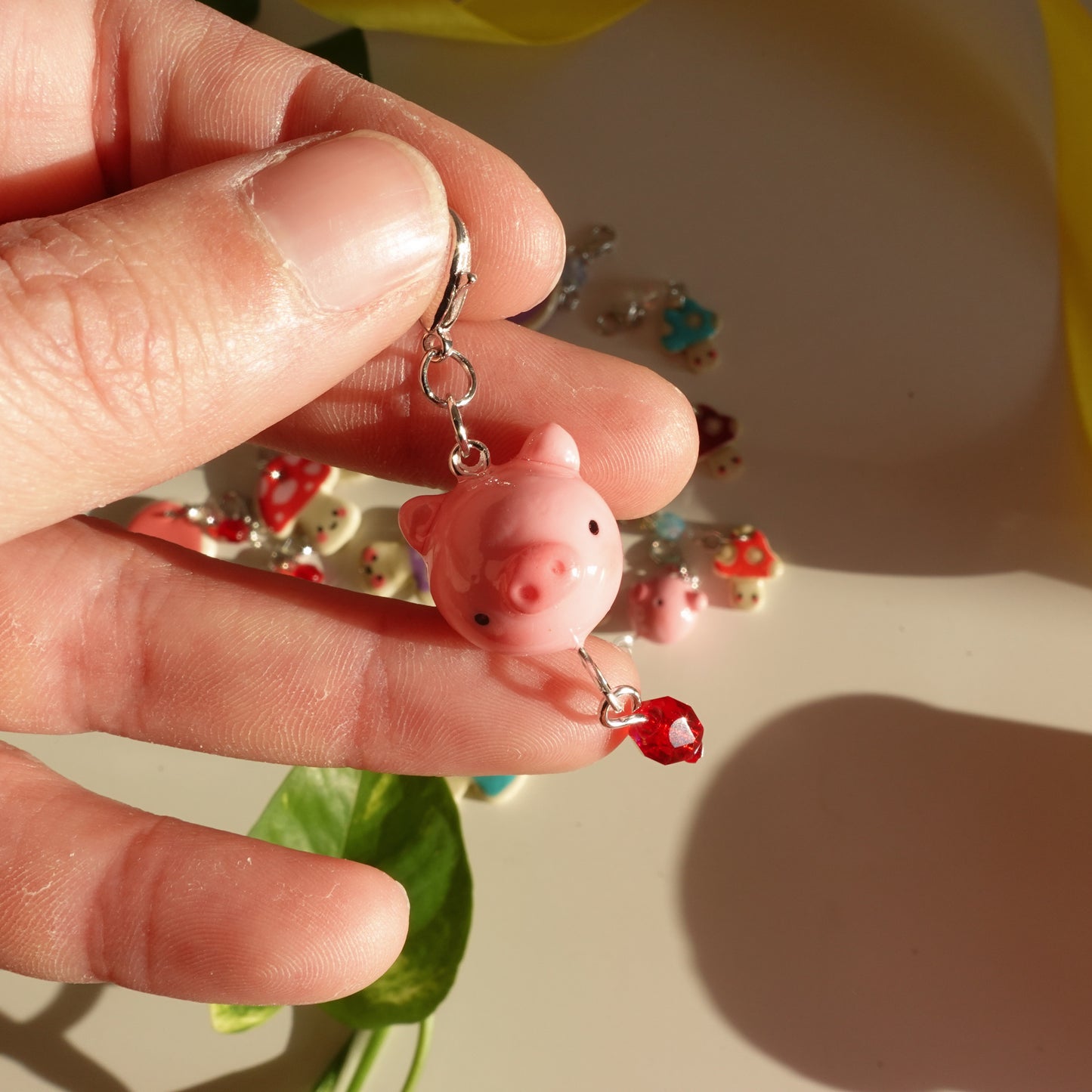 little pig lucky charm with a red bead out of polymer clay and covered with uv resin for durability with the bead more visible