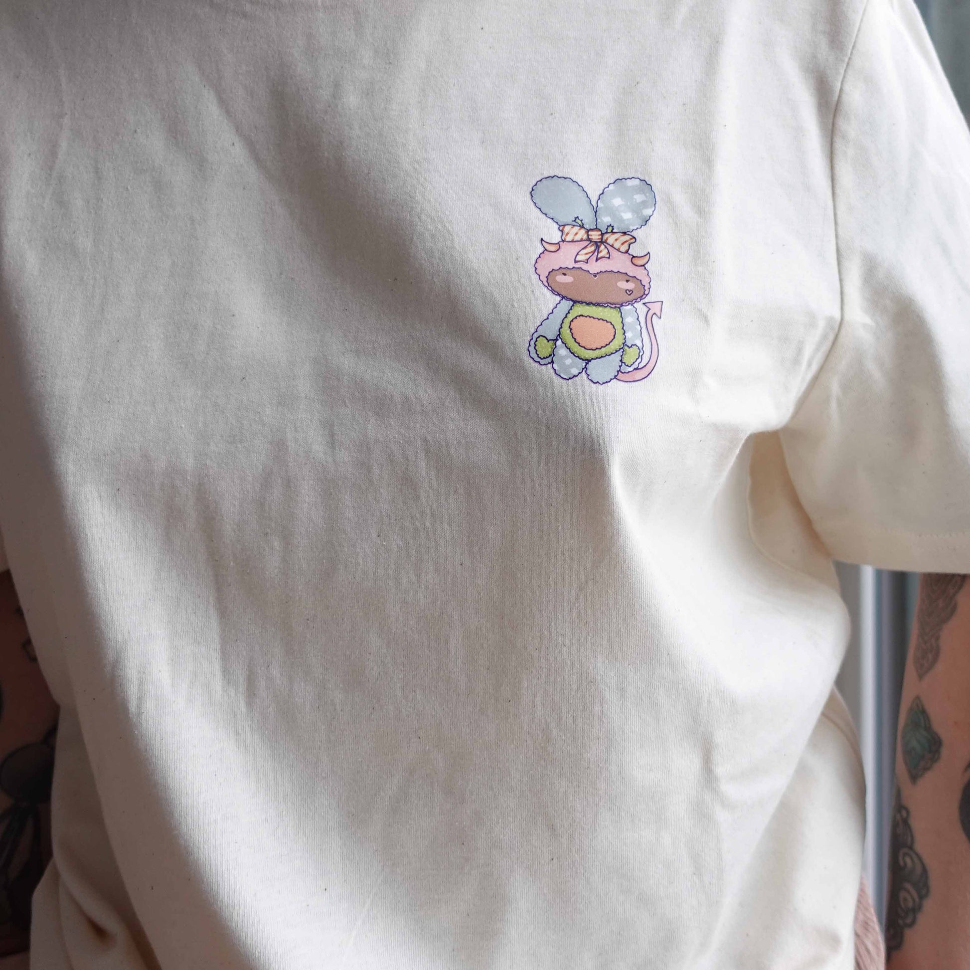 Front view and close up of the Fluff Club  t-shirt in natural raw color, featuring a original design by uncomfy cherry from the devil hearts sticker pack