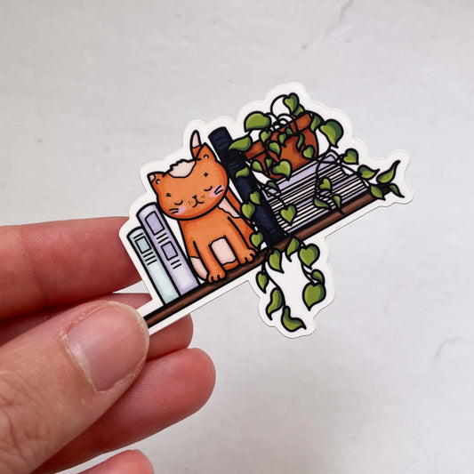 Book Nook Cat Sticker featuring a charming cat curled up in a book nook design, perfect for adding literary charm to laptops, notebooks, and water bottles