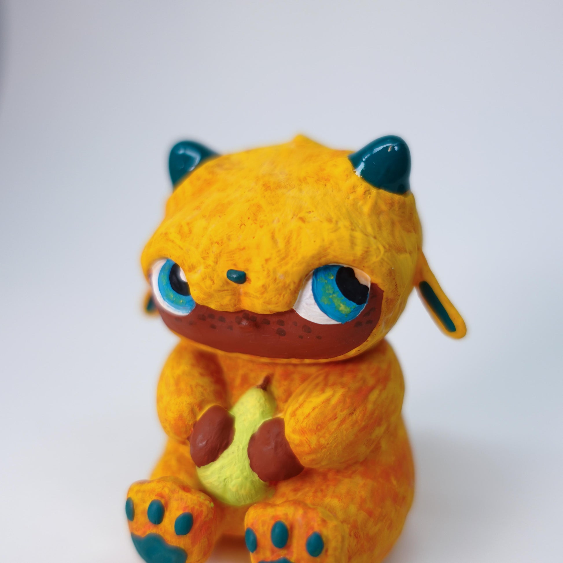 Small handmade Pear Gremlin sculpture with orange body, glossy horns, side-eye expression, 3D printed in resin, matte varnish, photographed on neutral background, one-of-a-kind.