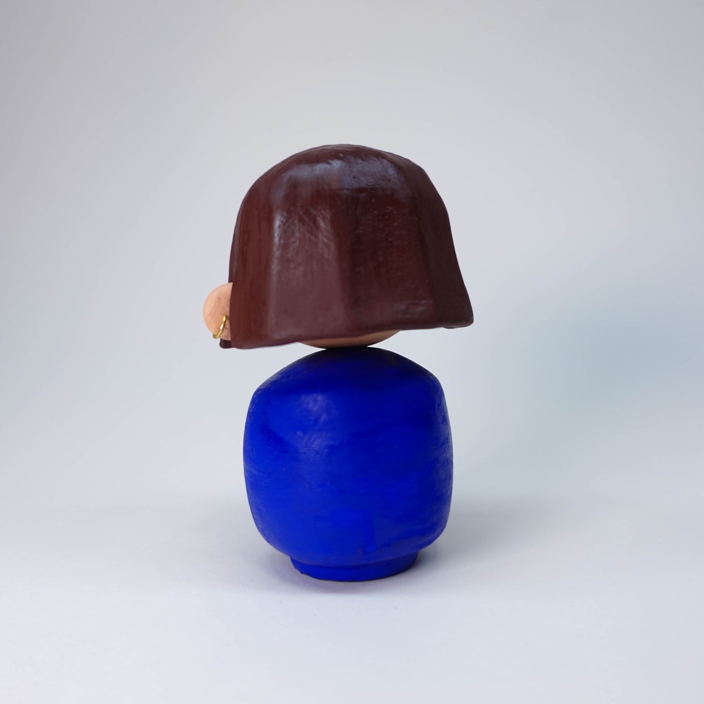 Püpi Bloom bold blue sculpture with brown hair and tiny held earring, hand-painted, one-of-a-kind collectible figure.