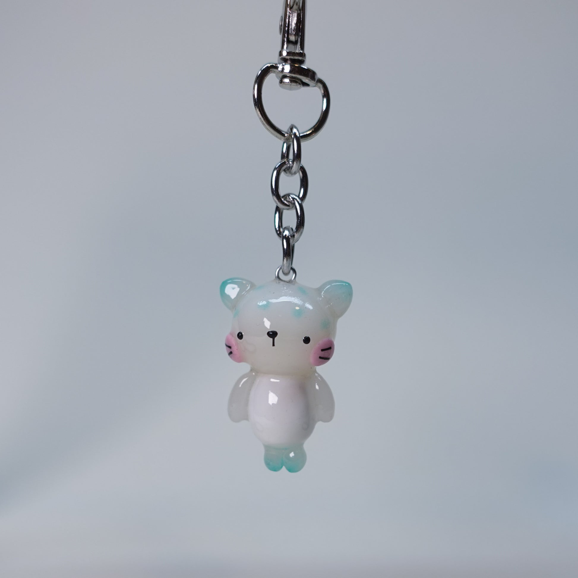 Handcrafted teal pastel cat keychain with smooth finish and playful small cat design, limited edition handmade accessory for keys or bags.