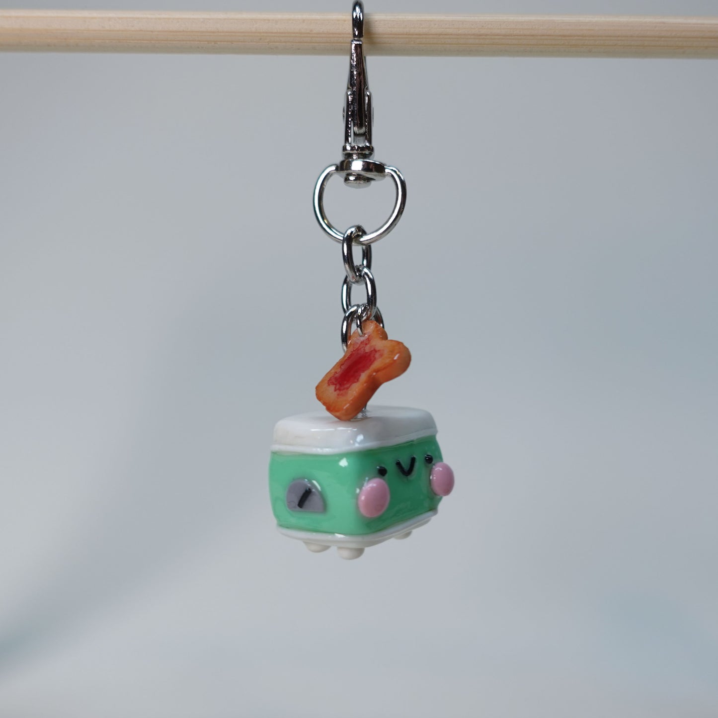 Handmade teal toaster keychain with dangling toast charm featuring red jam detail, playful pastel accessory for keys or bags, limited edition design.