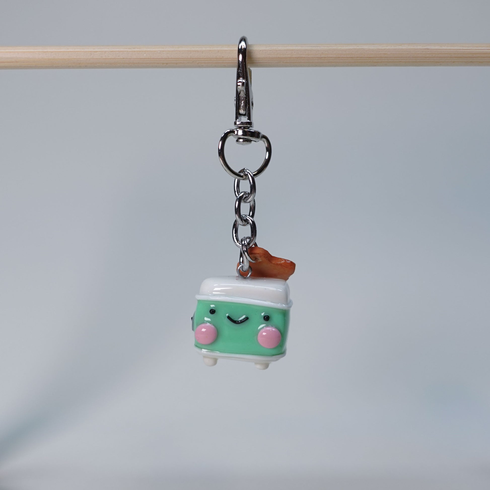 Teal handmade toaster keychain with a small hanging toast charm topped with jam, photographed against a soft neutral background.