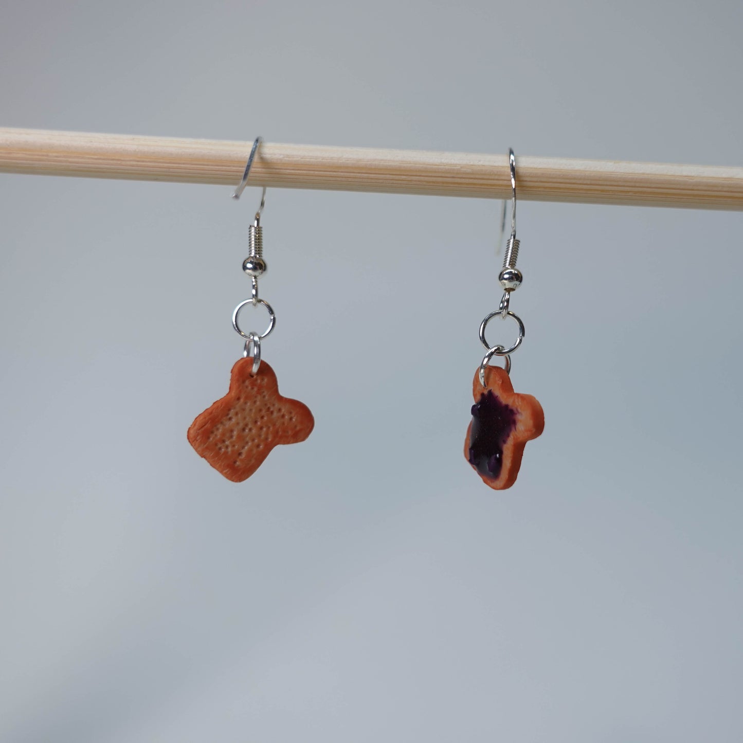 Set of five handmade Toast with Jam earrings, each pair unique with slight burn, blueberry jam, or strawberry jam topping, photographed on neutral background, limited edition.