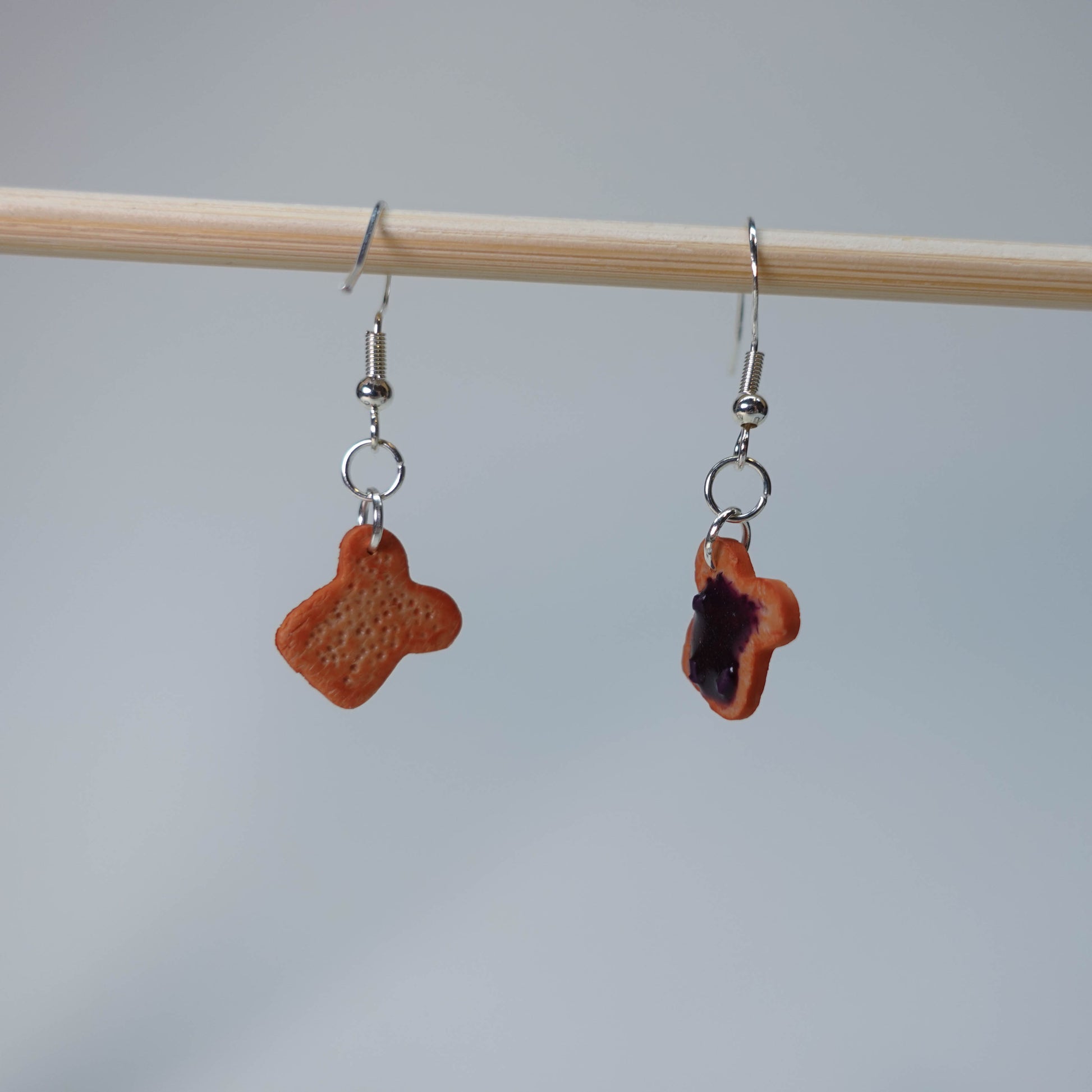 Set of five handmade Toast with Jam earrings, each pair unique with slight burn, blueberry jam, or strawberry jam topping, photographed on neutral background, limited edition.