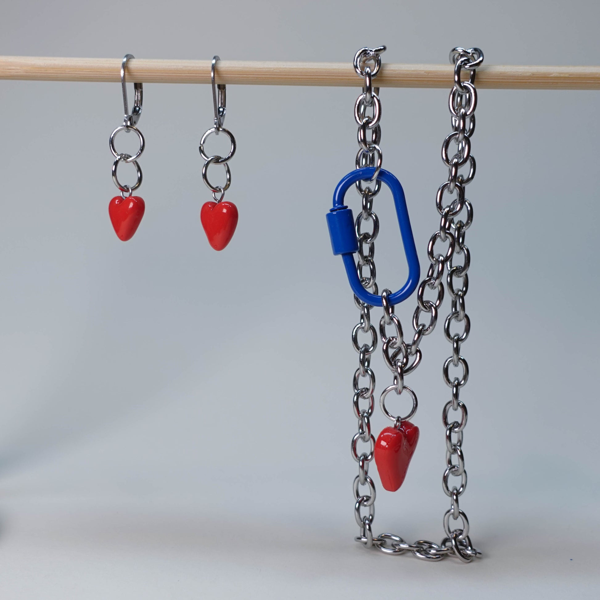 Set of handmade heart-shaped earrings with a matching statement necklace/choker featuring a blue carabiner, photographed on neutral background, limited edition jewelry set.