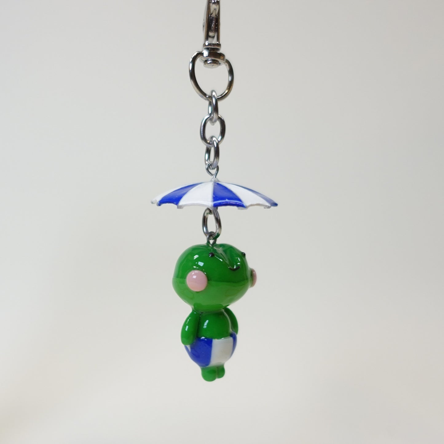 Handmade polymer clay frog keychain wearing a colorful summer umbrella hat with a glossy UV resin finish.