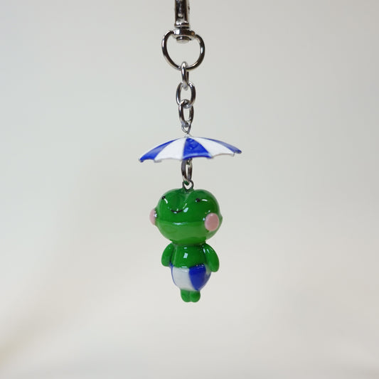 Handmade polymer clay frog keychain wearing a colorful summer umbrella hat with a glossy UV resin finish.