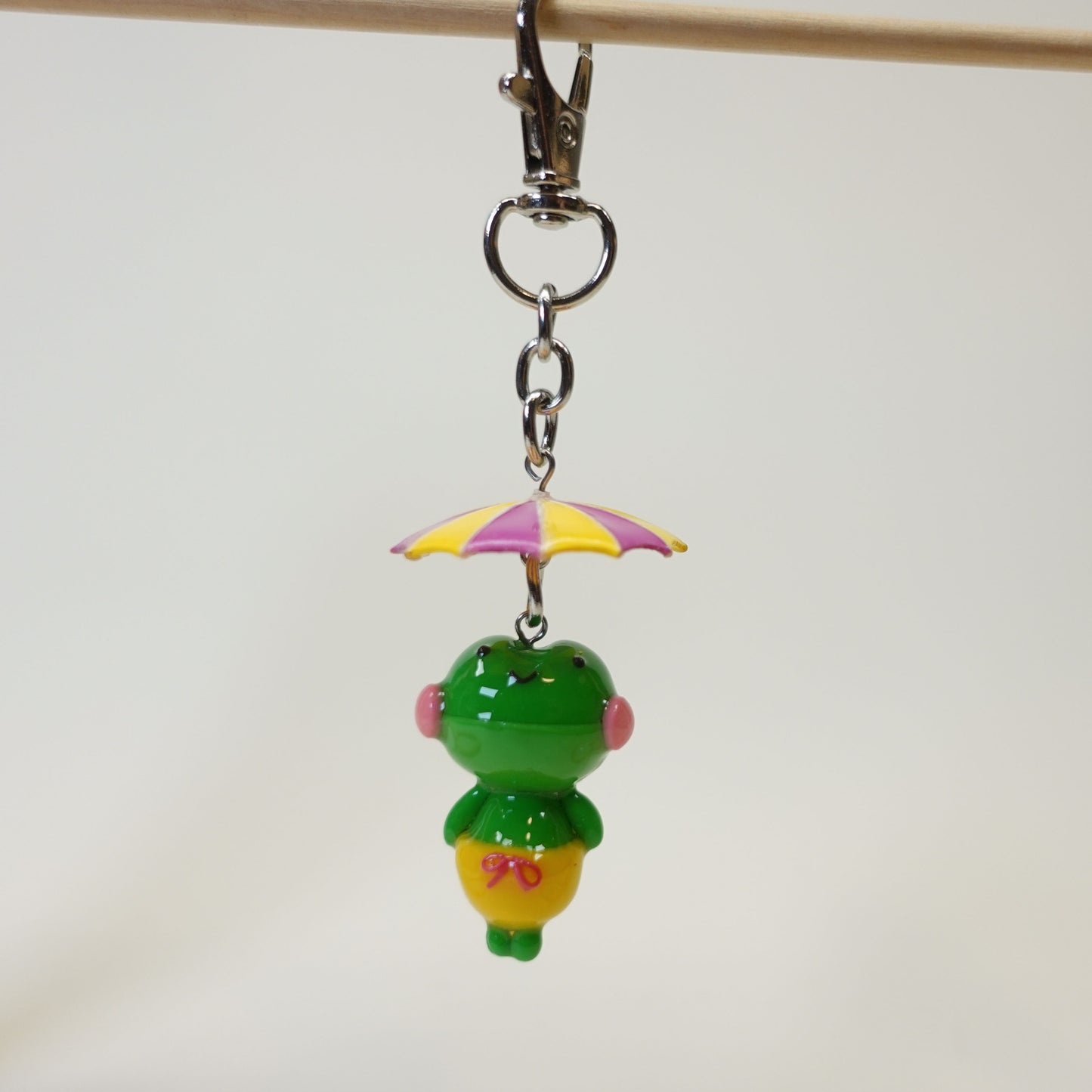 Handmade polymer clay frog keychain wearing a colorful summer umbrella hat with a glossy UV resin finish.