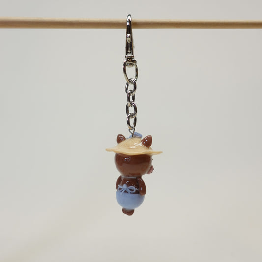 Handmade polymer clay cat keychain wearing a summer sunhat with a glossy resin coating.