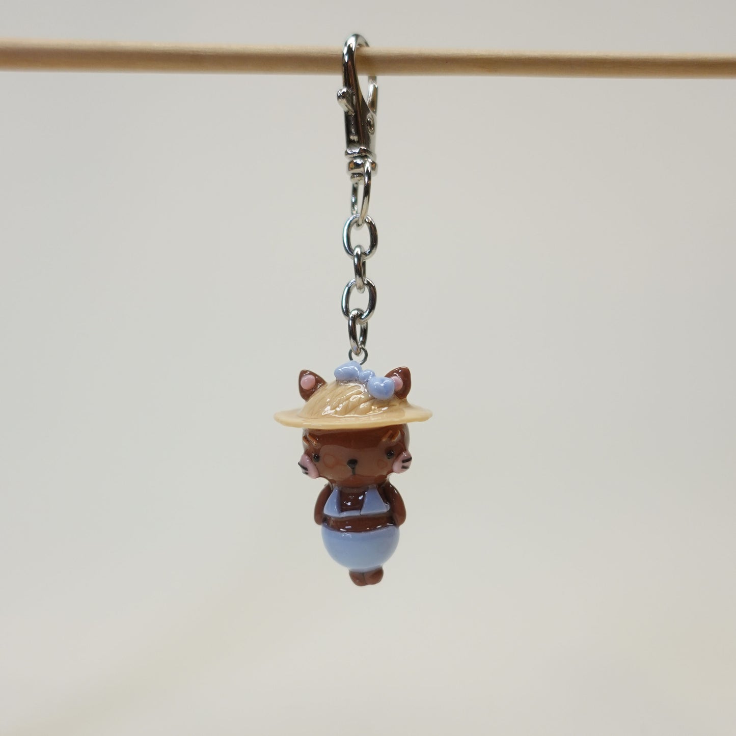Handmade polymer clay cat keychain wearing a summer sunhat with a glossy resin coating.