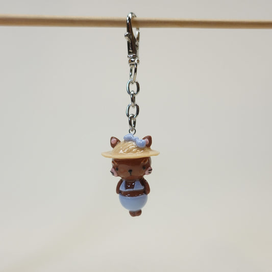 Handmade polymer clay cat keychain wearing a summer sunhat with a glossy resin coating.