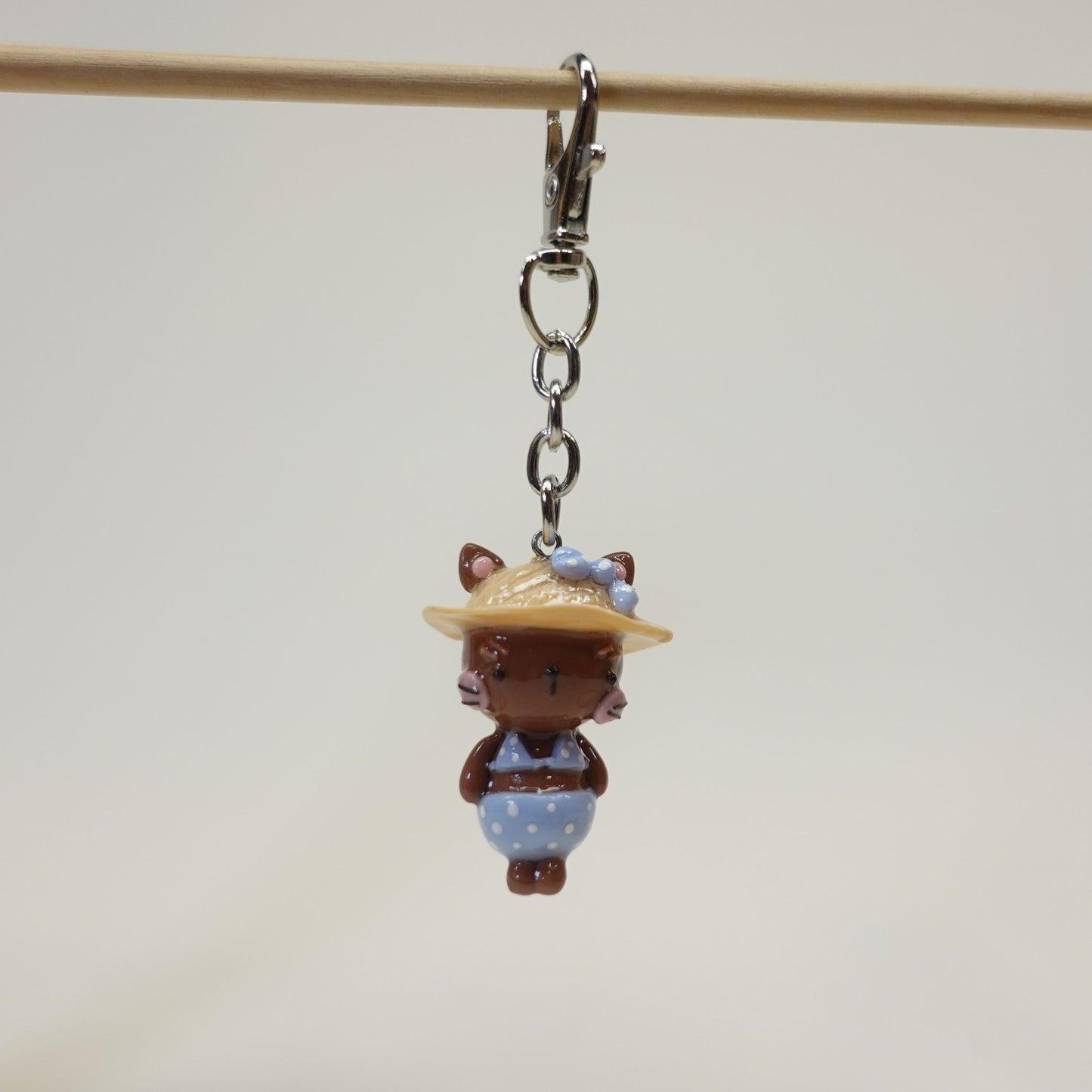 Handmade polymer clay cat keychain wearing a summer sunhat with a glossy resin coating.