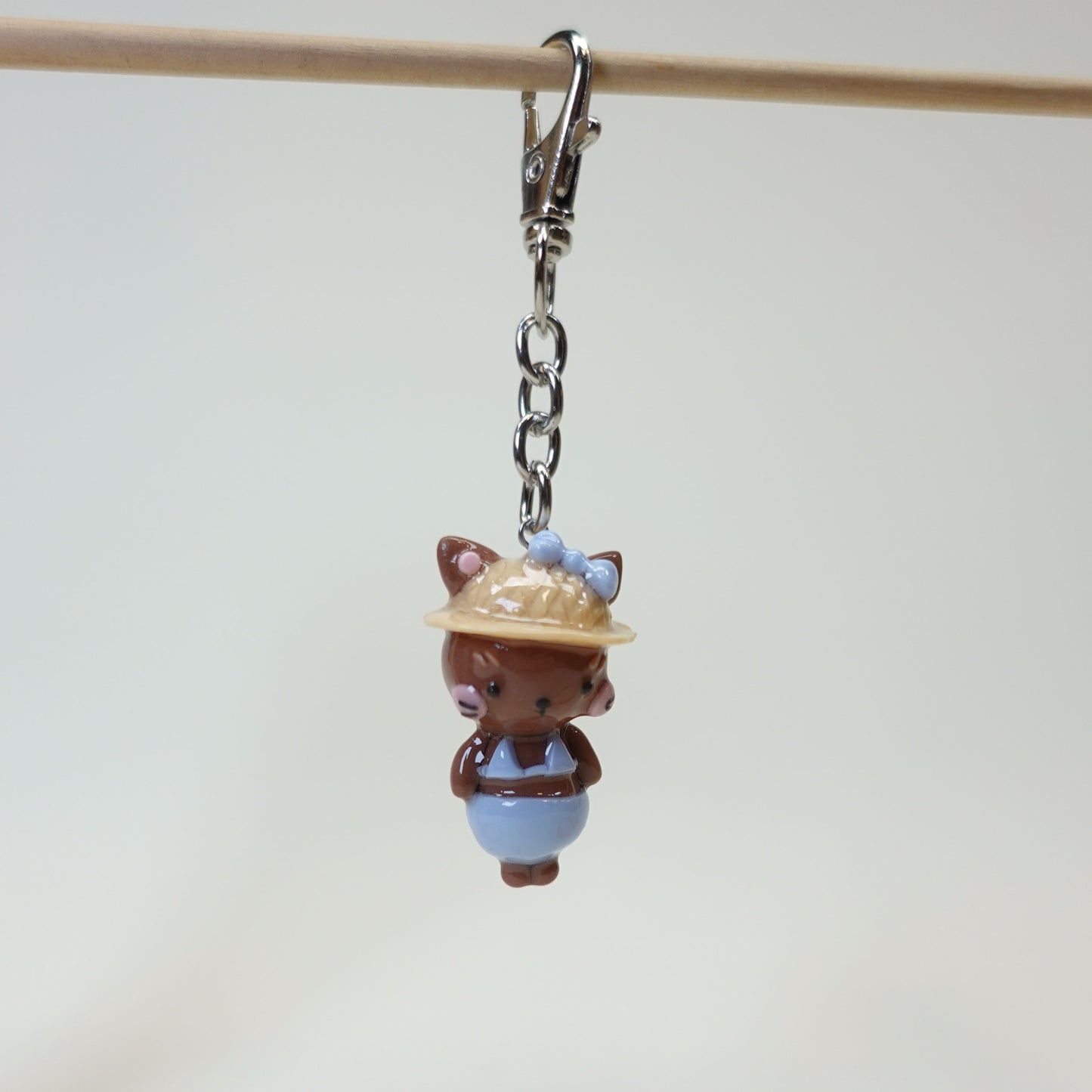 Handmade polymer clay cat keychain wearing a summer sunhat with a glossy resin coating.